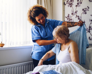 a female caregiver helping an elderly woman